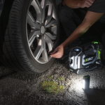 gonfleur 3 en 1 en train de gonfler une roue de voiture pendant la nuit, avec vue de la lampe portative