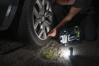 gonfleur 3 en 1 en train de gonfler une roue de voiture pendant la nuit, avec vue de la lampe portative